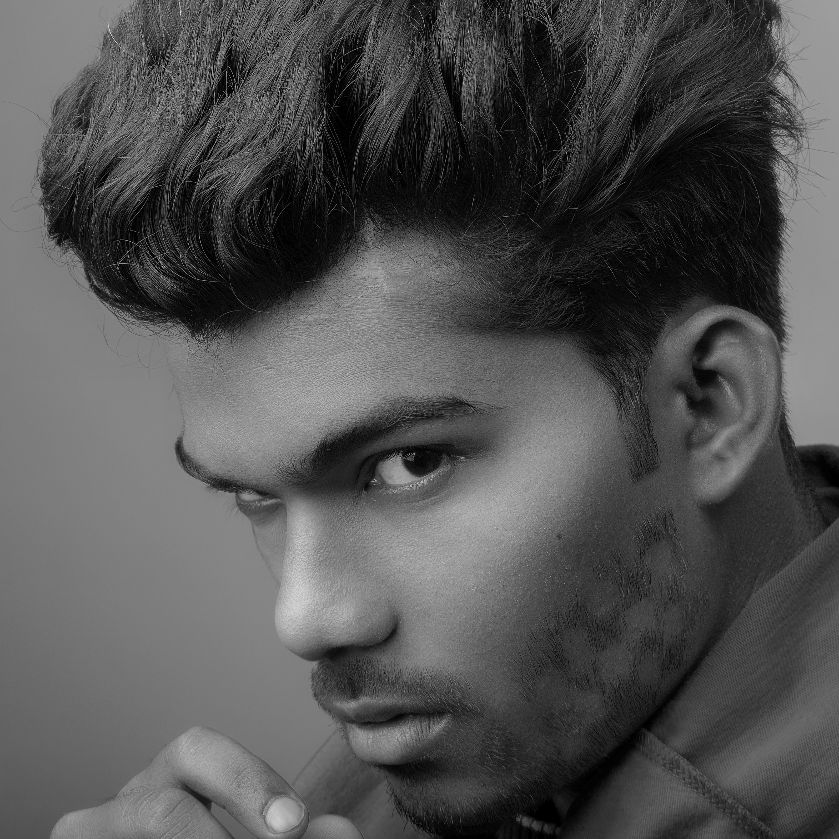 a man staring at the camera with a short-back and sides haircut, and stylized beard