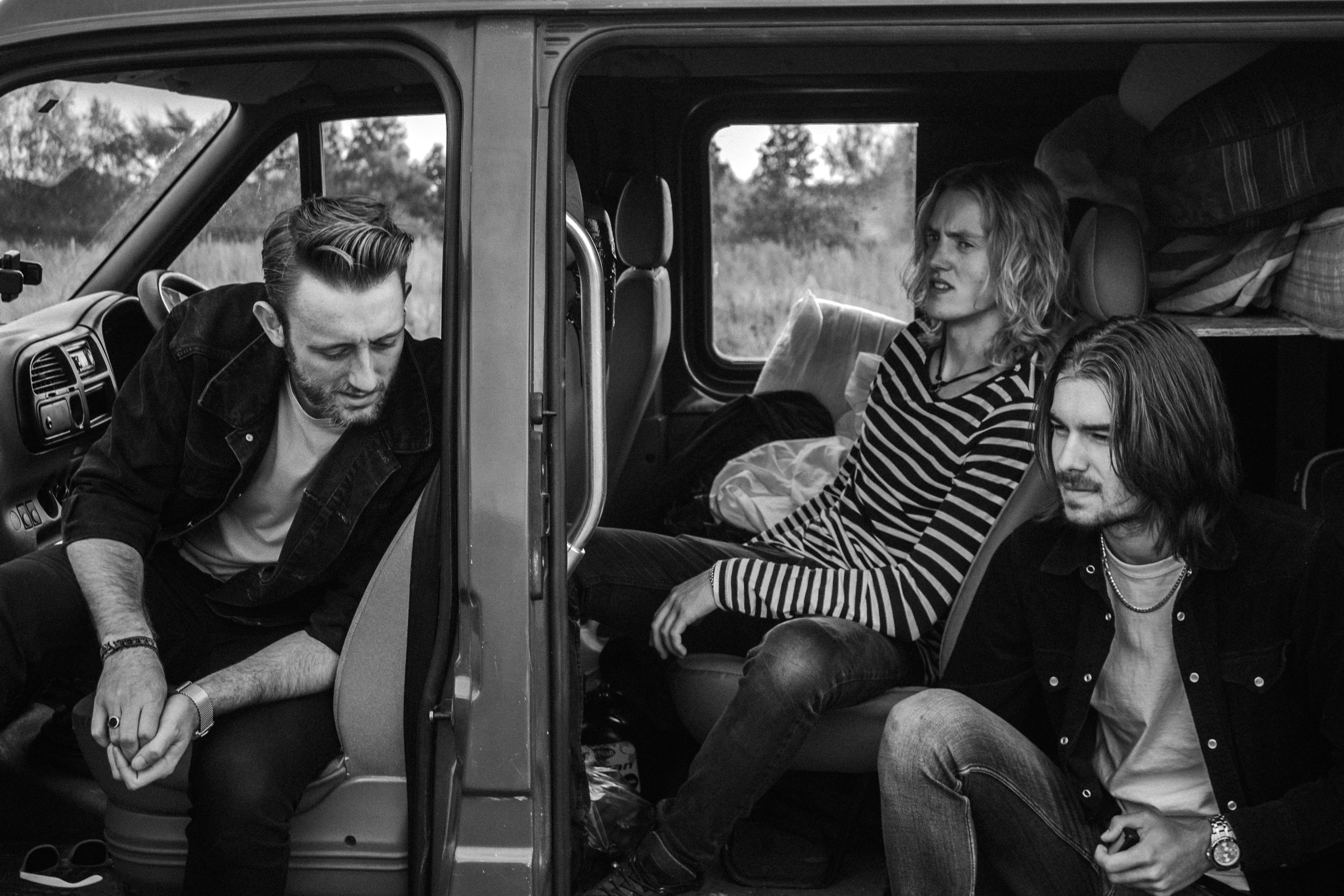 three man with long hair in a car